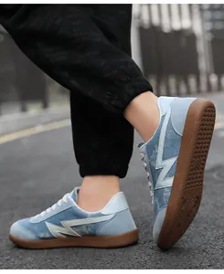 Detail of light blue denim sneakers with lightning motif and brown rubber traction sole