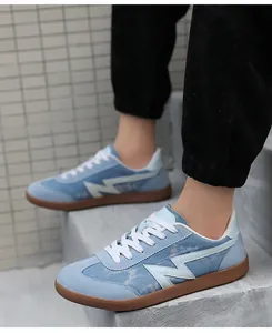 Detail of light blue denim sneakers with white logo and retro brown rubber gum sole