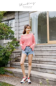 Outdoor lifestyle shot of women's mesh sneakers with red logo and denim shorts