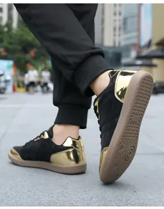 Dettaglio delle scarpe da ginnastica nere e oro con suole in gomma marrone resistenti in strada