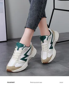 Macro shot of retro low-top sneakers featuring white leather and green contrast side stripes