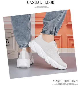 Close-up of white breathable mesh sneakers styled with light blue ripped denim jeans