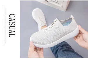 Close-up of white breathable mesh sneakers with flexible thick soles and pull tabs