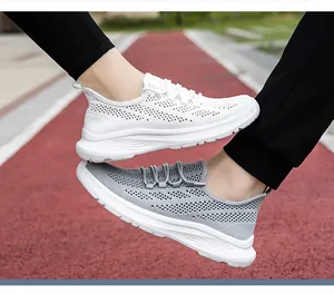 Dettaglio di sneakers in maglia traspirante su pista con suola bianca spessa e lacci