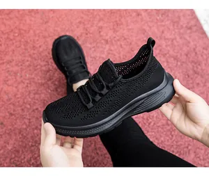 Dettaglio di sneaker nera in rete traspirante su sfondo rosso di pista sportiva