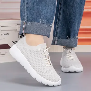 Light gray breathable knitted mesh sports sneakers with thick white soles on feet