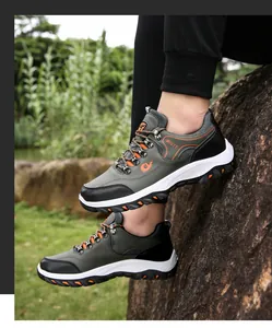 Detail of dark green trekking shoes with thick anti-slip soles on outdoor rocky terrain