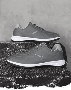Detail van donkergrijze leren casual sneakers met modieuze stiksels op steentextuur