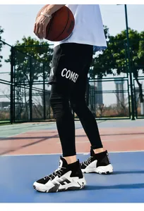 Gros plan de chaussures de basket montantes noir et blanc sur terrain extérieur sportif