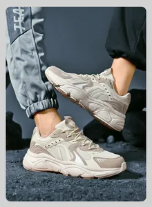 Detail of chunky dad sneakers showing beige mesh and suede textures on gravel ground
