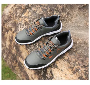 Detail view of military green hiking shoes with orange laces on natural stone background