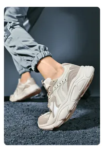 Close-up of chunky beige mesh dad sneakers with thick anti-slip soles on gravel ground
