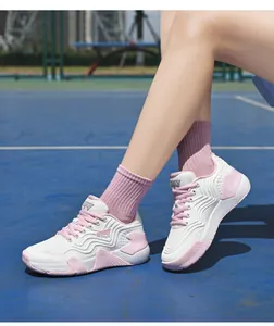 Détail de chaussure de badminton légère et respirante avec touches roses sur court bleu