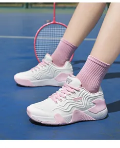 Détail de chaussures de badminton respirantes rose et blanc sur terrain de sport