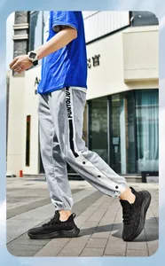 Detail view of grey jogger pants featuring side snap buttons and white lettered tape