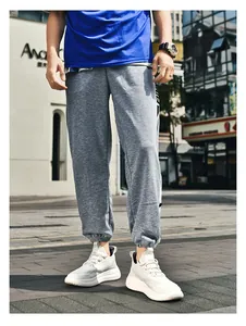Détail du jogging gris chiné avec ourlets resserrés et baskets blanches à semelles compensées