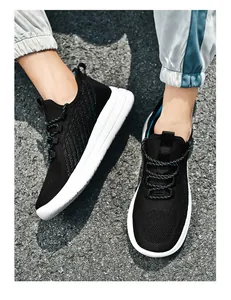 Vue rapprochée de baskets noires respirantes en maille fly-knit pour hommes au sol asphalté