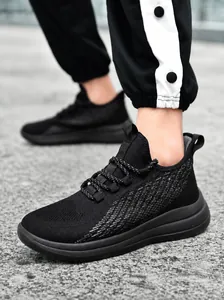Détail de la chaussure de course en maille flyknit noire pour hommes sur une route en gravier
