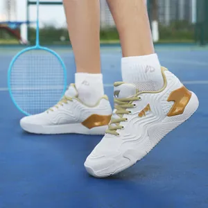 Chaussures de badminton respirantes blanc et or sur un terrain de sport bleu professionnel
