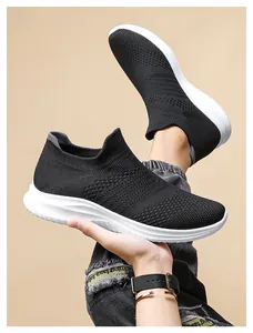 Detail shot of breathable black knit slip-on sneakers with cushioned white soles on model