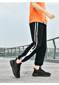 Détail de chaussures de course noires en maille et pantalon de jogging à bandes latérales