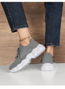 Detail of grey breathable mesh sneaker with thick white speckled sole worn on feet