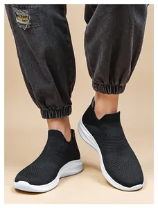 Close-up of black breathable knit sneakers with thick white cushioned soles on model feet