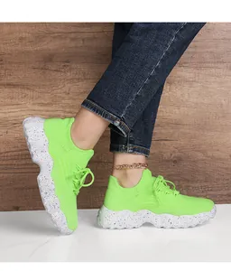 Detail view of fluorescent green knitted sneakers with white speckled platform soles