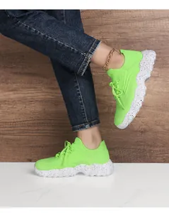 Close-up of fluorescent green knit mesh sneaker with thick white platform sole and splash paint
