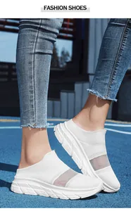 Close-up of white breathable mesh slip-on sports sneakers on a blue outdoor court surface