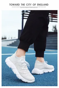 Detail eines weißen Strick-Sneakers mit dicker Sohle auf blauem Laufbahn-Hintergrund