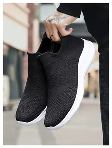 Close-up of lightweight black knit walking shoes with thick white soles held by hand