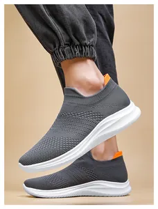 Side view of dark grey knitted slip-on walking shoes with white wavy thick sole and orange accents