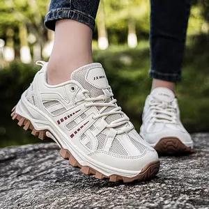 Outdoor hiking shoes in beige with chunky brown rubber soles on rocky terrain