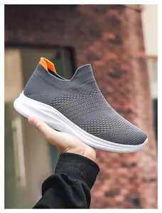 Detail of grey breathable knit sneakers featuring an orange heel tab and white thick sole