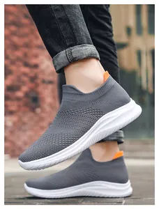 On-foot shot of grey breathable knit slip-on sneakers with white EVA soles on a street