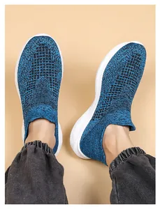 Close-up of blue fly-knit walking shoes with thick white soles on grey joggers