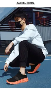 Outdoor shot of men's breathable black mesh slip-on sneakers with thick orange soles