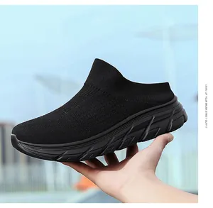 Detail of breathable knit upper and thick wave-patterned sole on black slip-on sneakers