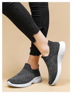 Close-up of breathable black fly-knit walking sneakers with thick white rubber soles