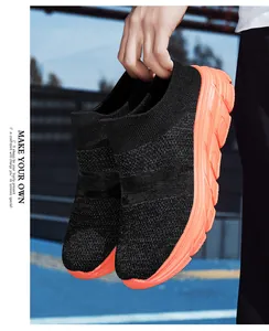Detail of breathable black knit upper and thick orange non-slip sole on walking shoes