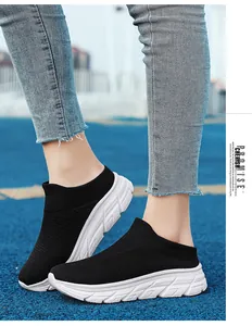 Detail of black knit slip-on mule sneakers with thick white soles on a blue track