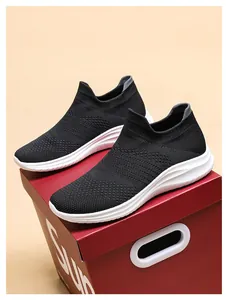 Detail of black knit sneakers with thick white soles placed on a red shoebox