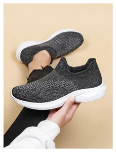 Detail of dark grey fly-knit slip-on sneakers with white cushioned soles for outdoor walking