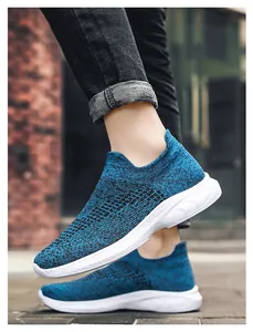 Detail shot of breathable blue knit slip-on sneakers with thick white soles on the street