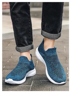 Close-up of blue knit slip-on sneakers for men with white athletic soles on pavement