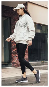 Outdoor shot of grey flyknit sneakers worn with casual hoodie and ripped denim jeans