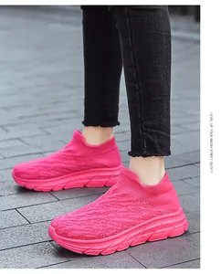 Close-up of pink breathable knitted mesh sneakers on street pavement with chunky sole