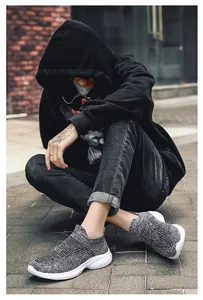 Detailed close-up of grey and black knit sneakers with thick white soles on a male model
