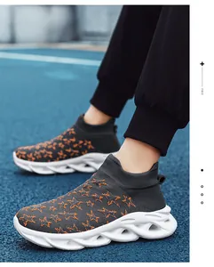 Dettaglio di sneaker in maglia grigia con stelle arancioni su una pista di atletica